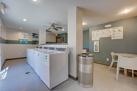 A white dishwasher is in a room with a table and chairs.