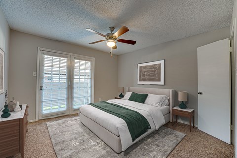 A bedroom with a bed, nightstand, and a ceiling fan.