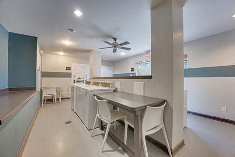 A kitchen with white appliances and white chairs.