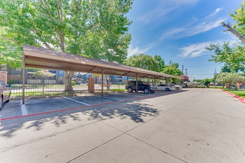 A parking lot with a covered area and a fence.