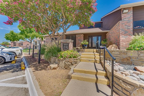 A house with a stone wall and steps leading to the front door.