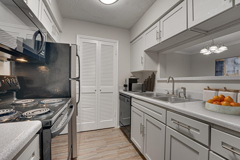 A kitchen with a black stove top oven and white cabinets.