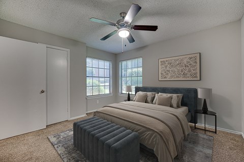 A bedroom with a bed, pillows, a ceiling fan, and a window with blinds.