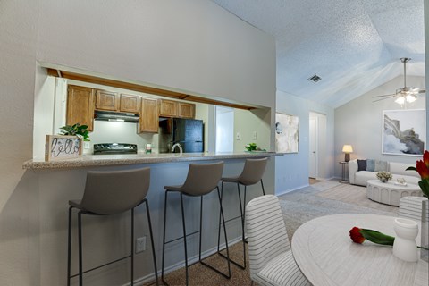 A kitchen with a bar area and chairs.