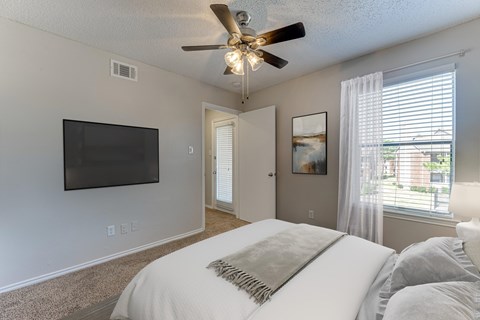 A bedroom with a large bed and a flat screen TV mounted on the wall.