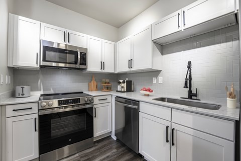 A modern kitchen with white cabinets and stainless steel appliances.