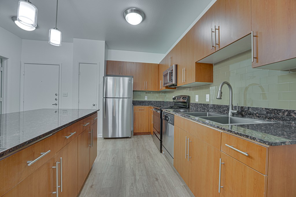 A kitchen with wooden cabinets and a granite countertop. at Vue Greenville, Dallas, TX