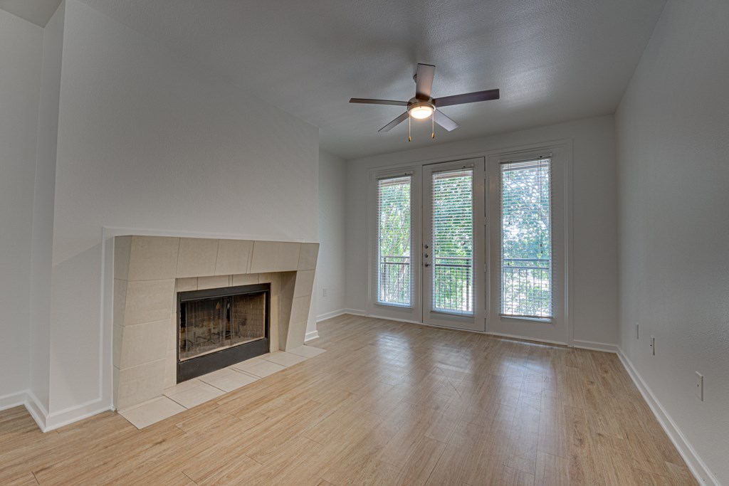 A room with a fireplace and sliding glass doors. at Vue Greenville, Texas