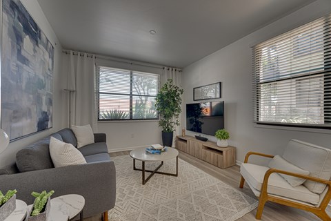 A living room with a grey couch, a white armchair, a coffee table, and a large painting on the wall.