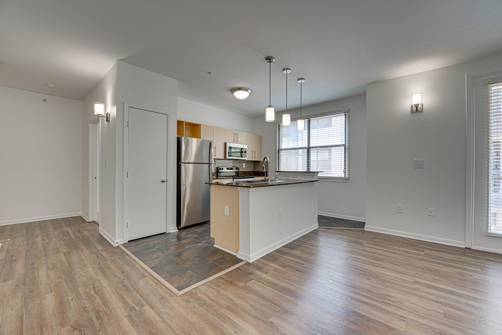 A kitchen area with a refrigerator, sink, and cabinets. at Vue Live Oak, Dallas, Texas