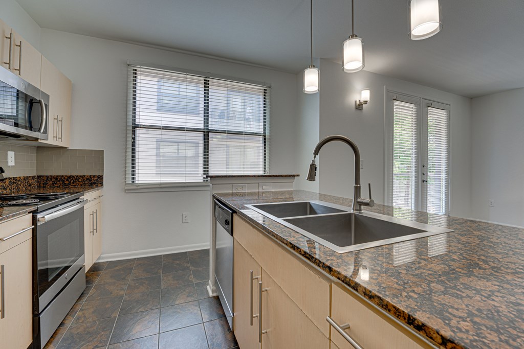 A kitchen with a granite countertop and stainless steel appliances. at Vue Live Oak, Texas, 75204