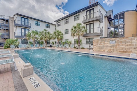 Resort style pool with palm trees and lounge chairs at Vue Live Oak Apartments, Texas, 75204