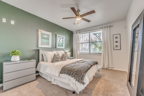 Bedroom with sage accent wall and ceiling fan at Vue Live Oak Apartments, Texas