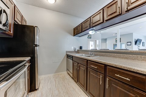 A kitchen with brown cabinets and a black refrigerator.