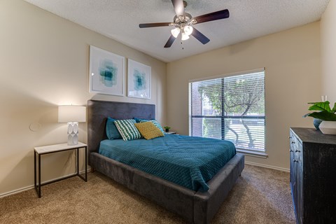 A bedroom with a bed, nightstand, and a ceiling fan.