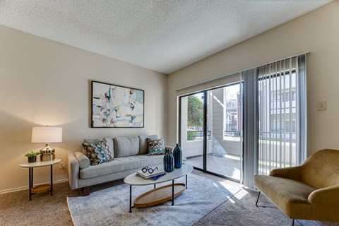 A living room with a couch, a chair, a coffee table, and a painting on the wall.