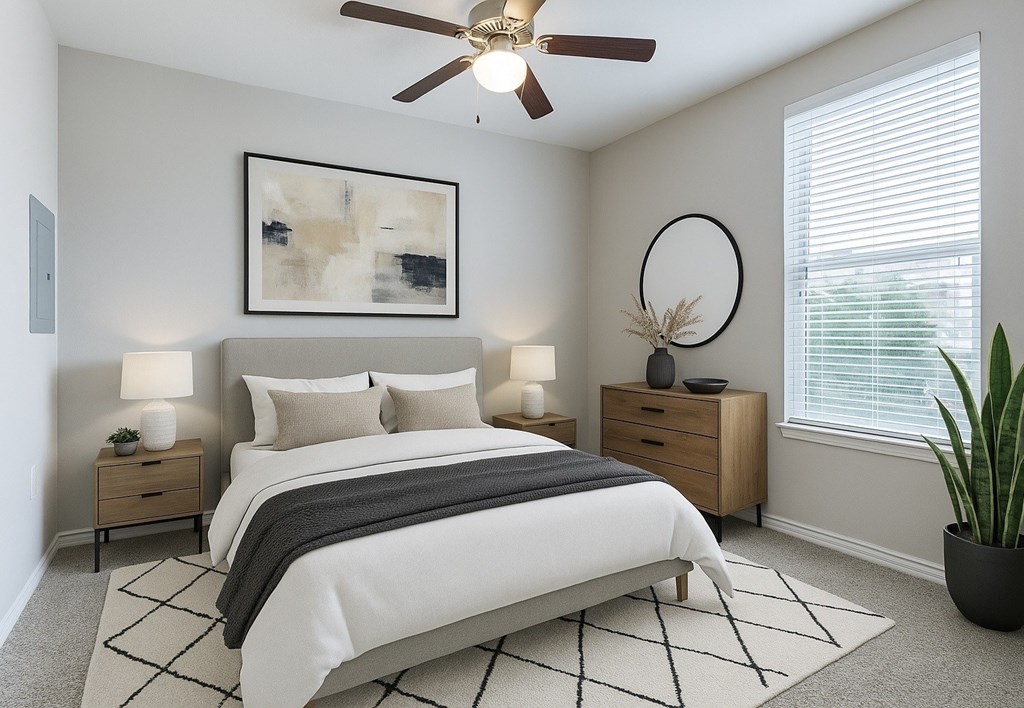 A bedroom with a large bed, a ceiling fan, and a painting on the wall.