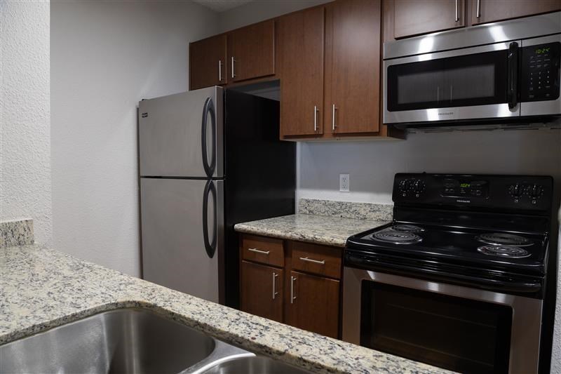 A kitchen with a stainless steel refrigerator, microwave, and oven.
