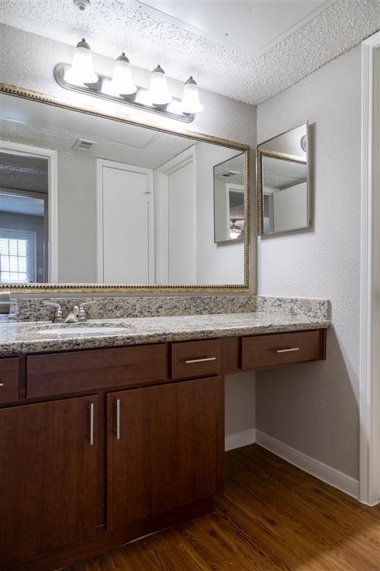 A bathroom with a marble counter top and wooden cabinets.