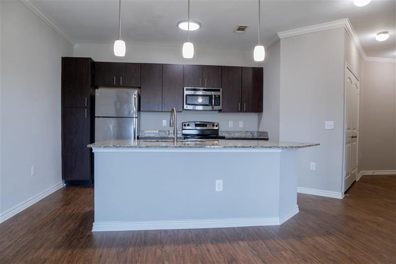 A kitchen with a white island and dark brown cabinets.