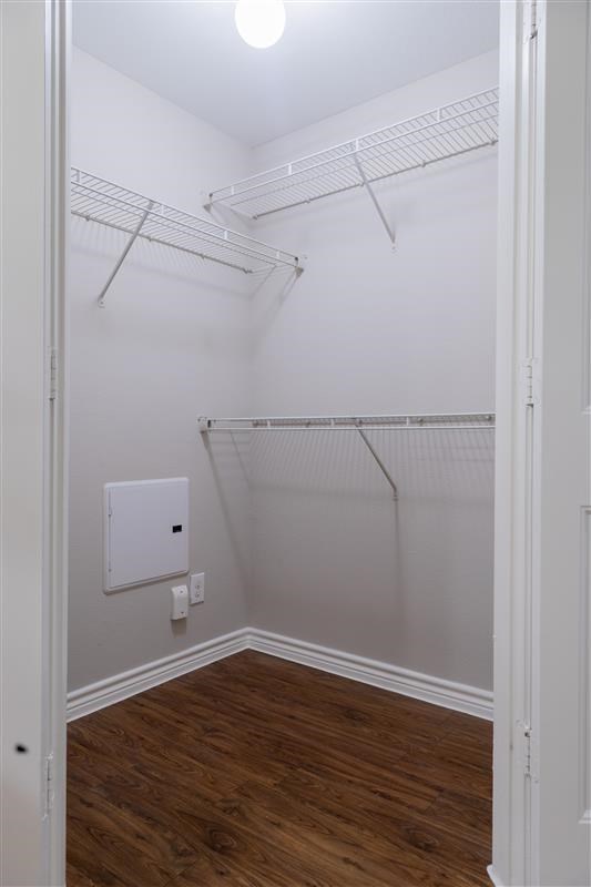 A white closet with a wood floor and a white electrical box on the wall.