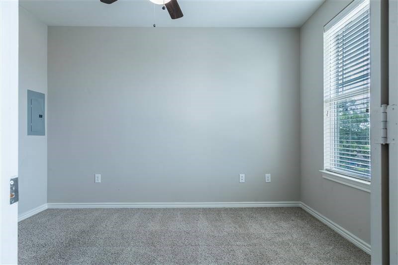 A room with a carpet floor and a window with blinds.