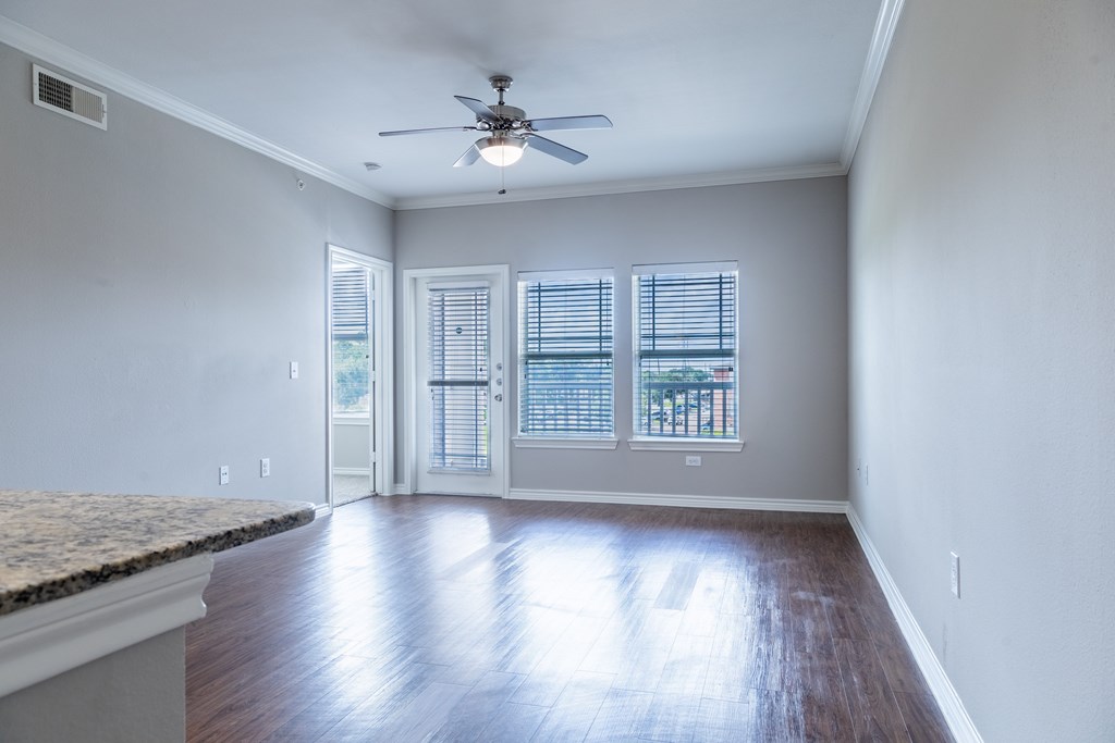 A room with a ceiling fan and sliding glass doors.