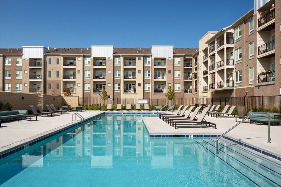 a swimming pool with lounge chairs in front of an apartment building