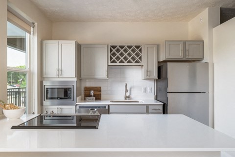 A modern kitchen with a stainless steel refrigerator and white countertops.