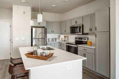 A kitchen with a white counter top and grey cabinets.