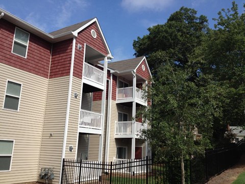 A red and beige apartment building with a black fence in front.
