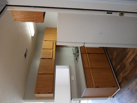 A view of a kitchen with wooden cabinets and a white counter.