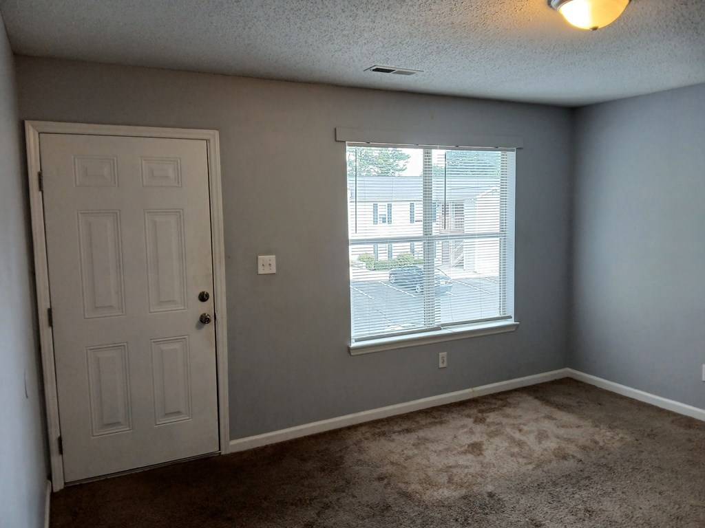 A room with a white door and a window with blinds.