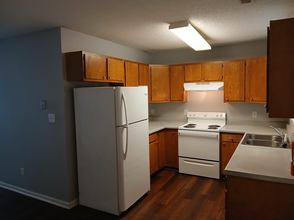A kitchen with a white refrigerator, stove, and sink.