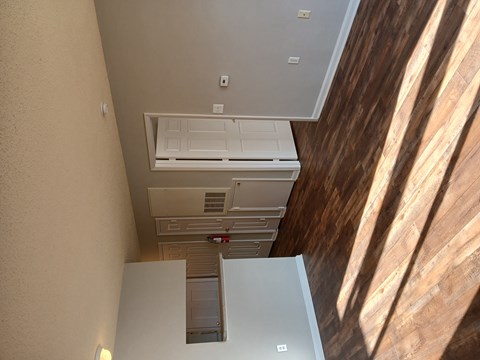 A white air conditioning unit is installed on the ceiling of a room with wooden walls.
