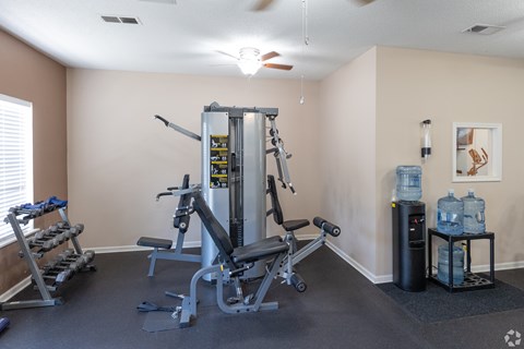 A home gym with a weight machine, a bench, and a water cooler.