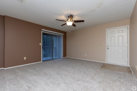 A room with a ceiling fan and a sliding glass door.