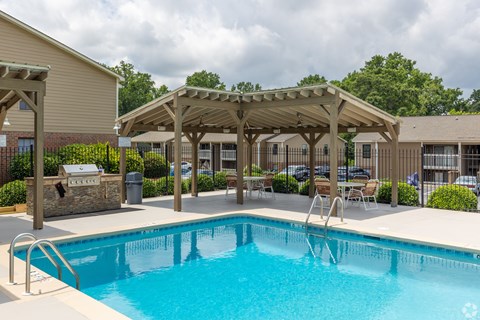 A swimming pool with a wooden pergola over it.