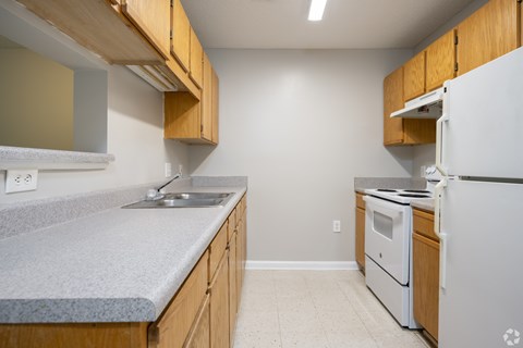 A kitchen with a white refrigerator and wooden cabinets.