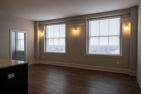 an empty living room with two windows and a door