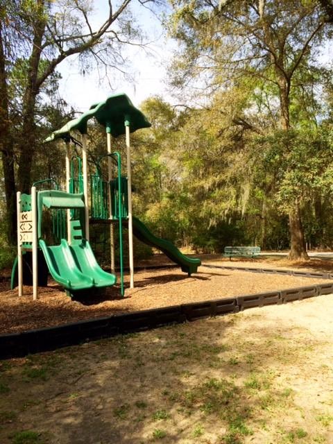 a playground with a green slide in a park