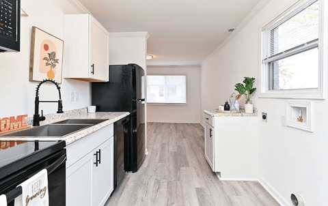 A kitchen with black appliances and white cabinets.