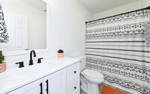 A white bathroom with a black and white shower curtain.