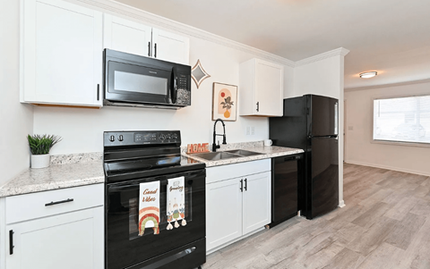 A kitchen with black appliances and white cabinets.