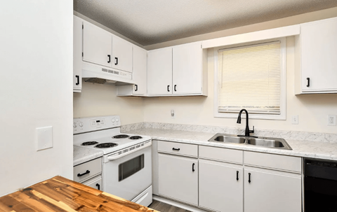 A kitchen with white cabinets and a wooden counter top.