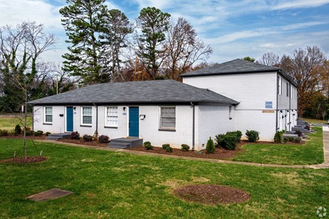 A white house with a grey roof and a blue door.
