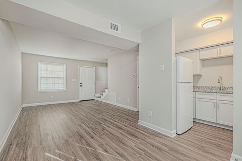A spacious room with wooden flooring and white walls.
