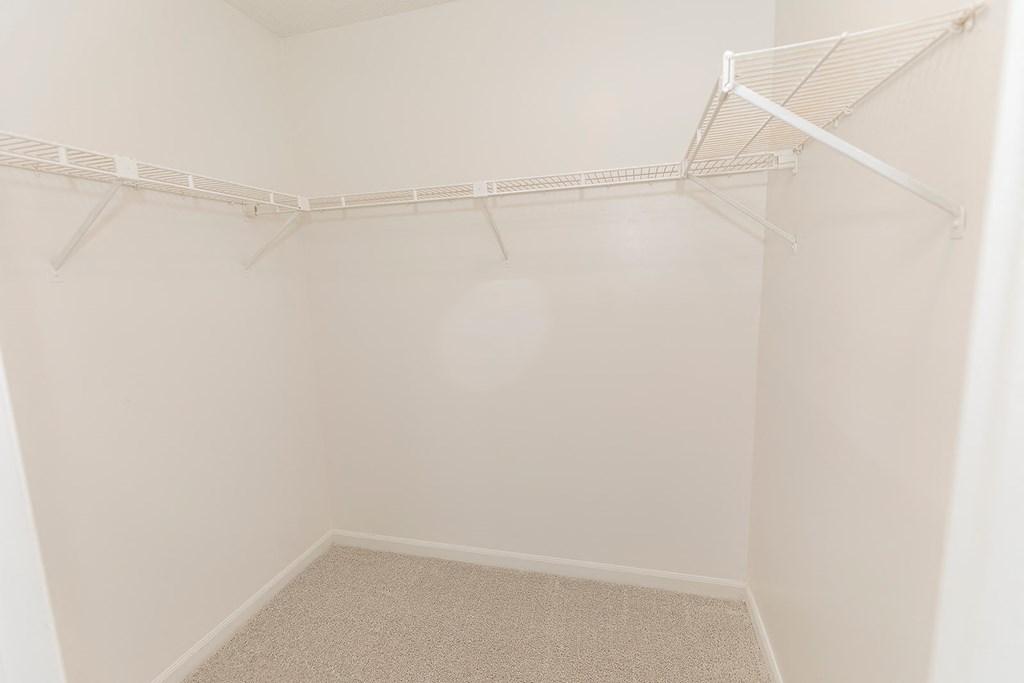 a walk in closet with white walls and a white rack on the ceiling