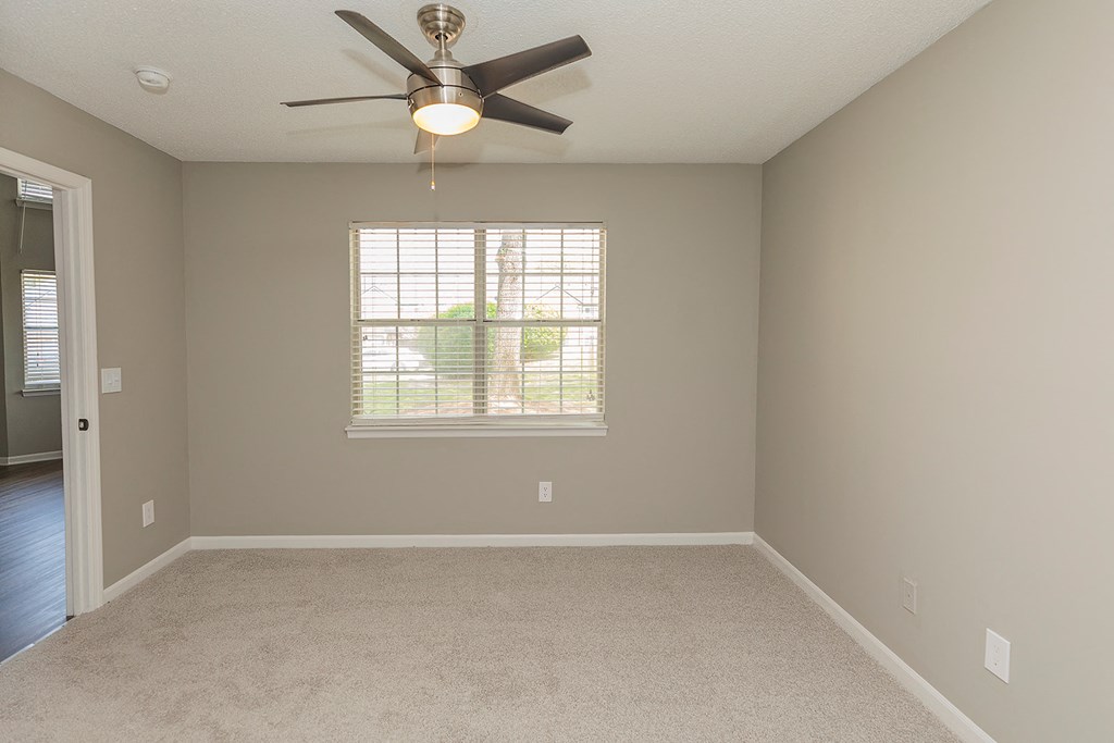 an empty room with a ceiling fan and a window