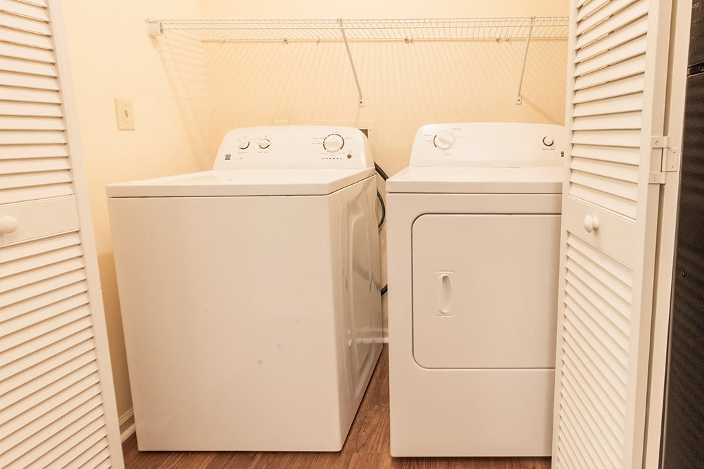 a washer and dryer in a room with white blinds